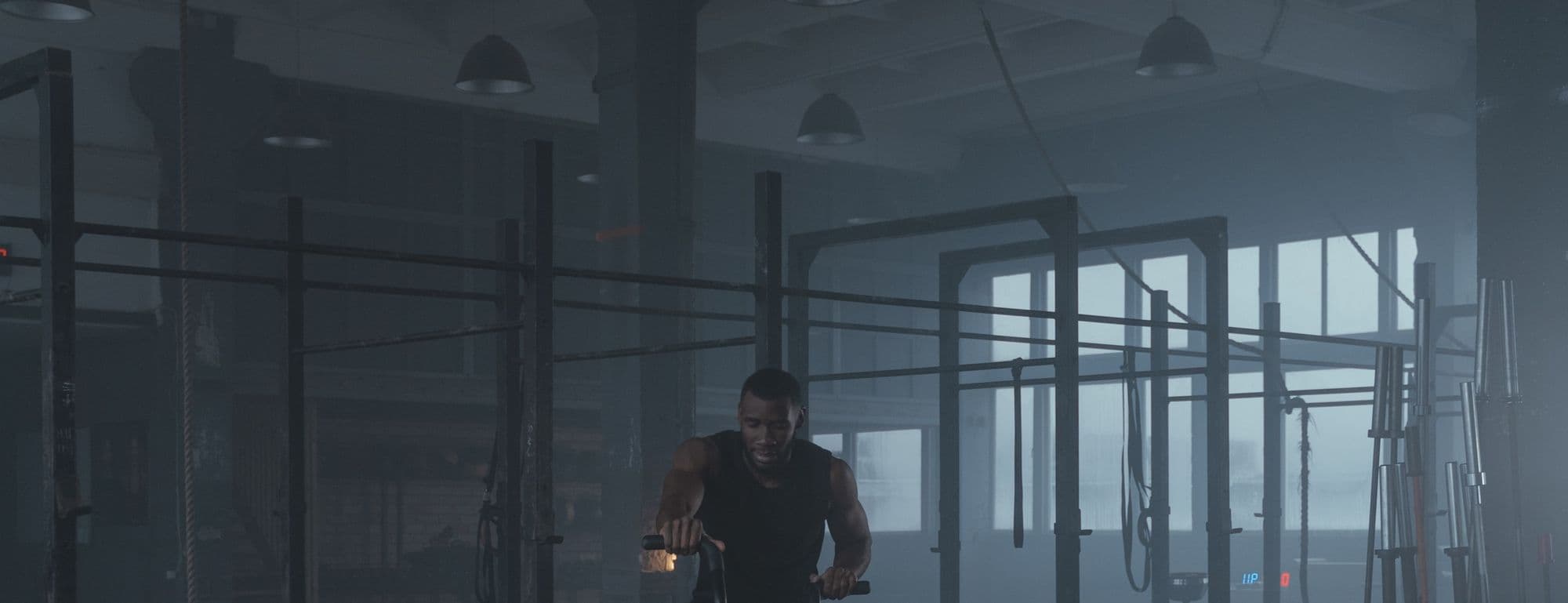 Un athlete seul sur un air bike dans une salle sombre