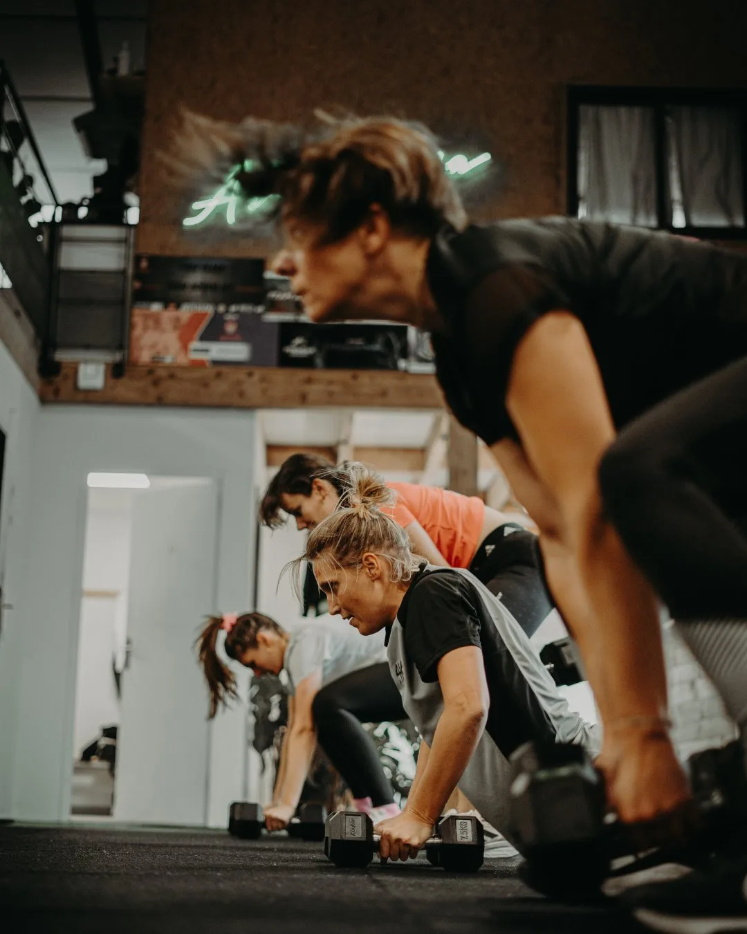 Cours collectif chez Artemisia CrossFit, enseigne néon visible au fond