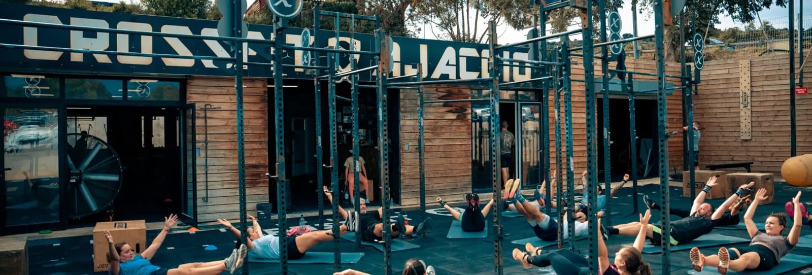 Cours collectif sous le rig extérieur de CrossFit Ajaccio, enseigne sur la façade bois