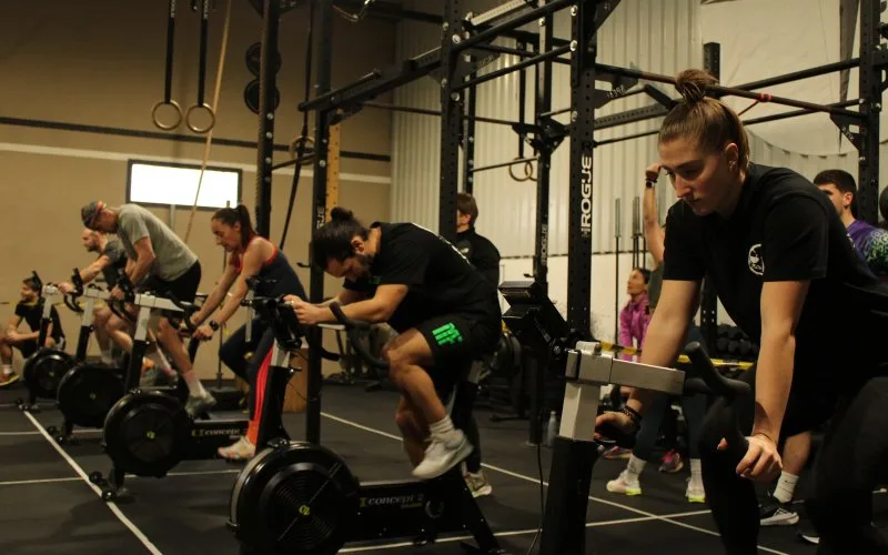 Cours collectif sur assault bikes chez CrossFit Corte, rig et anneaux en arrière-plan